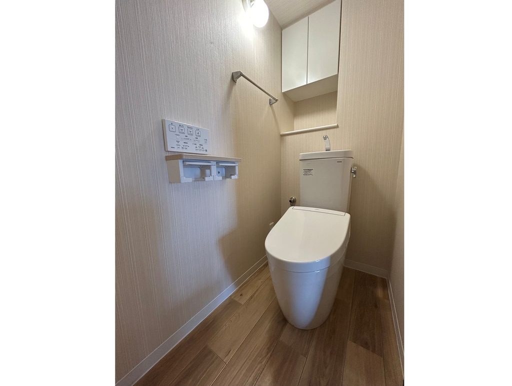 宇治市のトイレリフォーム完了後、すっきりとした最新トイレと収納棚、木目調床の施工事例
